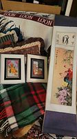 Image showing Asian floral and calligraphy scroll and two framed prints partially covered with plaid fabric and other textile items