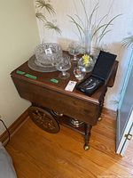 Wood tea cart with various glassware and a boxed wine opener set on top, showing overall condition and style of cart.