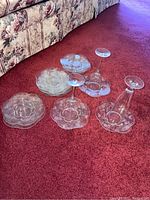 Top-down view of etched glass plates and three stemmed wine glasses.