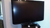 Front view of black LG flat screen TV on oval stand, screen off.