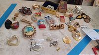 Wide shot showing assortment of pins, brooches, pendants on table.