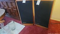 Pair of Marantz speakers standing side by side with black mesh fronts and wood grain finish on the sides.