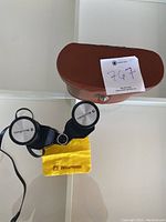 Binoculars with carrying case and cleaning cloth shown on a white surface.