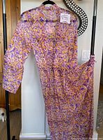 Full view of colorful sheer robe hanging on hanger showing front side with sleeves and lace-up waist detail.