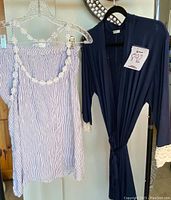 Navy blue robe and striped pajama shorts hanging on hangers, showing lace details and fabric texture.