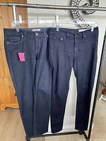 Front view of two pairs of black skinny jeans hanging on a rack.