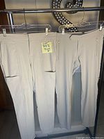 Front view of two beige women's pants hanging on hangers showing front pockets and belt loops, size 8