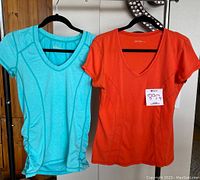 Two Zella women's yoga tops hanging side by side on black hangers, showing front view with size large indicated