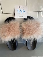 Top view showing pair of pink feather slides on black footbeds with feathers covering toes.