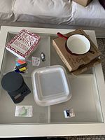 Full lot view showing cookbook, enamel pan in box, digital scale, plastic container, measuring spoons, thermometer, and toothbrush base