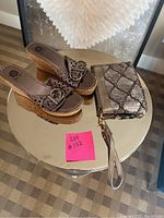 Pair of brown cork wedge sandals with beaded straps and matching small clutch purse with bead detailing on round silver table