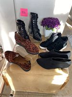 Photo shows four pairs of women's shoes: black lace-up ankle boots, leopard print suede loafers, black suede leopard print sneakers, and black stretch neoprene heels. Shoes are size 7.5M.
