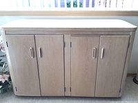 Front view of the white washed oak buffet cabinet showing four doors with recessed handles and wood grain finish.