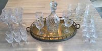 Overview of all glassware and brass tray, showing decanter in center on tray, surrounded by stemmed cut crystal and short glasses