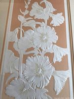 Close up of embossed flowers on a peach-orange background showing detailed white and beige floral design