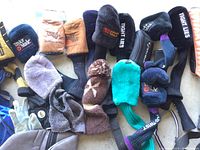 Photo showing a variety of golf club head covers, gloves, and knit caps in multiple colors and brands.