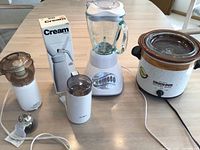 Photo of Rival slow cooker, Oster blender, Sunbeam chopper, cream whipper box and white coffee grinder on table