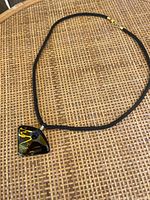 Full necklace with black cord and triangular black enamel pendant with gold pattern.