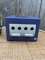 Front view of blue Nintendo GameCube showing four controller ports and two memory card slots with connected cables.