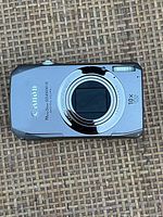 Front view of Canon PowerShot SD4500 IS camera showing lens, flash, and branding.