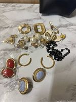 Full assortment of mixed jewelry pieces placed on a marble surface, including rings, earrings, and beaded accessories.