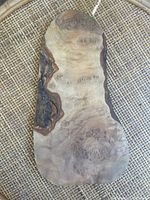 First live edge wooden slab showing unique wood grain and some bark remnants on edges.