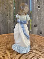 Back view showing the light blue bow and ruffle detail on the girl's white dress.