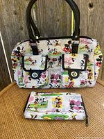 Front view of the Minnie Mouse-themed purse with two front pockets and matching wallet set on a wooden surface.