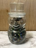 Front view of vintage Pillsbury Doughboy glass jar filled with marbles.