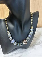 Photo of vintage enamel bead necklace displayed on black mannequin bust showing multicolored enamel beads on gold-tone chain.