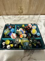 Photo showing the entire collection of marbles in a compartmentalized display case with clear lid.