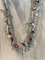 Front view of vintage necklace showing assorted charms featuring a mix of colored beads, metallic discs, and small pendants.