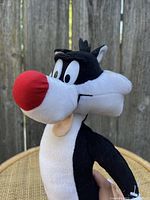 Front and side view of Sylvester plush showing detailed red nose, black and white fur, embroidered eyes, and facial features.