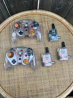 Top view of two wireless translucent GameCube controllers and three small wireless receivers with antennas on a round wicker table
