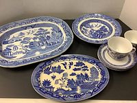 Photo showing large serving platter, medium serving bowl, two cups, four saucers all with blue willow pattern