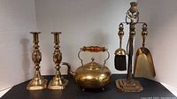 Full set showing two candlesticks, brass kettle, and brass fireplace tools with stand.