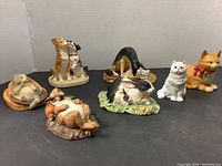 Seven handcrafted ceramic animal figurines displayed together with various animals including dogs, cats, and rabbits.