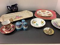 Full view of the dish set arranged together including plates, serving tray, cup and saucer, salt and pepper shakers, and small decorative dishes
