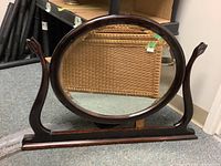 Full front view of vintage oval mirror with wood frame and base stand showing shape and size