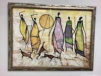Full view of the framed painted cloth artwork showing abstract figures and animals with a sun/moon in background.