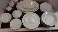 Display of various plates, bowls, cups and saucers with leaf design on white porcelain.