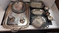 Overview of entire lot showing large tray, smaller plates, candlesticks, and small handled cups