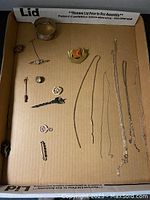 Overall view of 17 assorted jewelry pieces laid in cardboard box