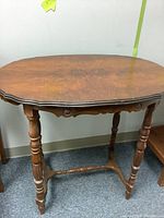 Side view of vintage oval wooden table with turned legs and stretcher base.