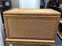 Front view of wicker trunk, showing woven wicker construction and plywood lining edge.