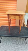Front view of antique wooden table showing single drawer and turned legs.