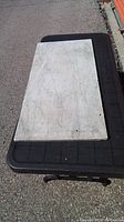 Full view of rectangular antique marble slab placed on a black platform outdoors, showing overall size and surface.