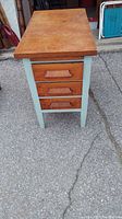 Front view showing three wooden drawers with wooden handles and painted sides.