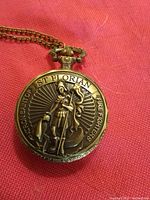 Front view of pocket watch showing embossed Saint Florian figure and text.