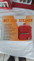Photo of the original boxed hot dog steamer showing front and top with product features and image.